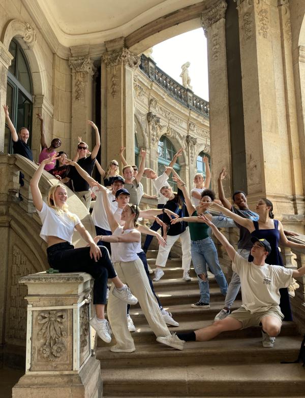 Students pose in ballet positions on stone steps.