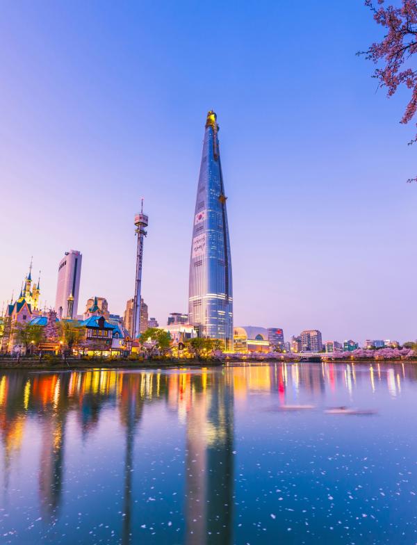 Seoul, South Korea's cityscape at sunset. The sky is pink, and in the foreground of the city is a body of water.