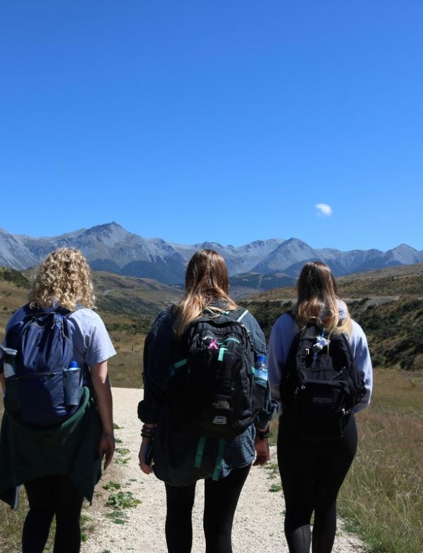 three students hiking toward a mountain range in Canterbury, Aotearoa New Zealand