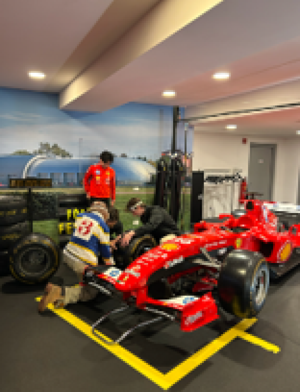 Three individuals viewing a race car up close.