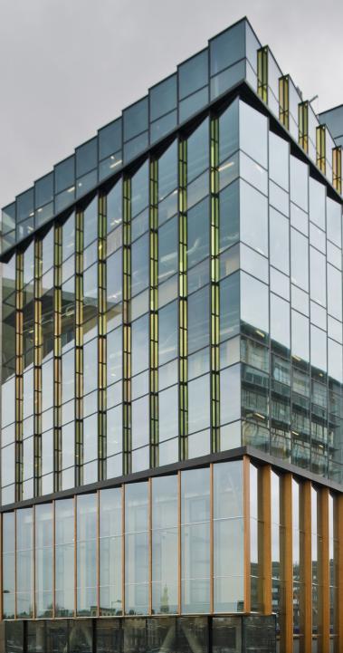 A large, modern building sits on the Conservatorium van Amsterdam's campus with reflective windows.