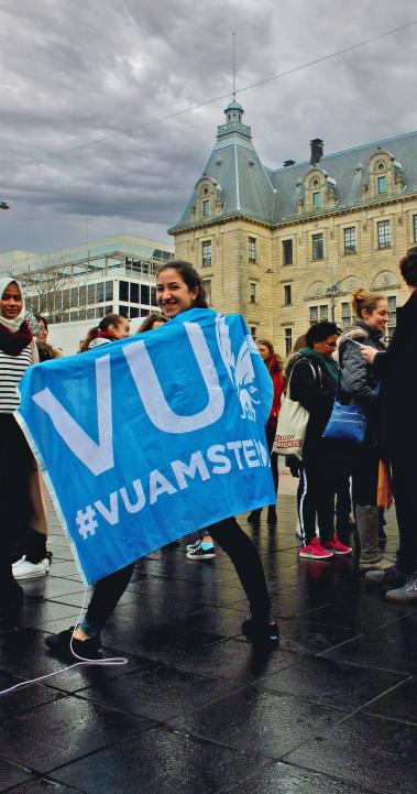 a student walking with a VU flag on a rainy day