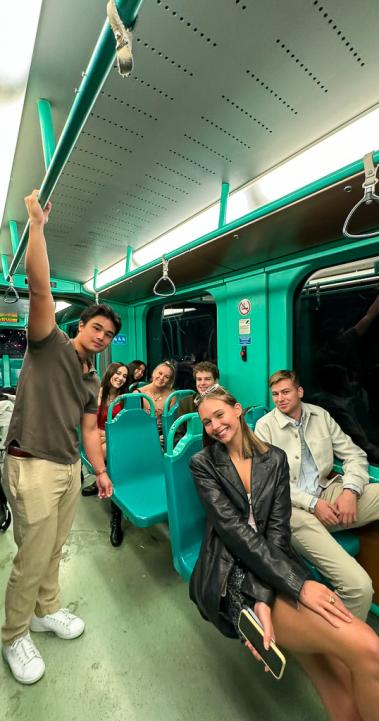 Several smiling students riding public transportation together