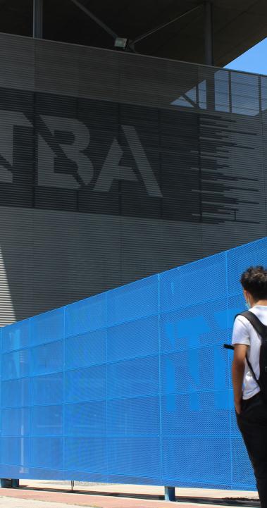 a student wearing a backpack walking toward an ITBA building