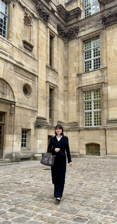 Student in business attire walking in front of parisian building