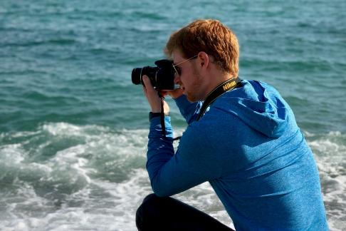a student takes a photo of the ocean on the beach in Barcelona