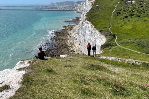 Students explore the rocky inclines off the coast of Dover on a sunny day.