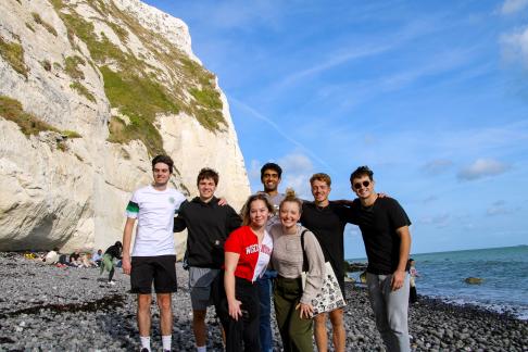 group of students standing in a group on a beach smiling