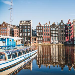 boats sit in Amsterdam Centraal Canal in front of traditional Amsterdam architecture