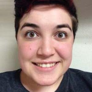 Sunset over a calm sea with distant smokestacks. This alt text was added with Al; accuracy may vary.