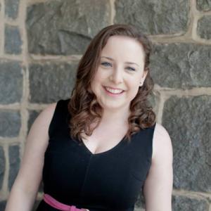 Smiling woman with long hair in a patterned top. This alt text was added with Al; accuracy may vary.