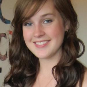 Smiling woman with long hair in a softly lit room. This alt text was added with Al; accuracy may vary.