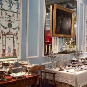 Elegant dining room with ornate decor, blue walls, and a table set with silverware and dishes. This alt text was added with Al; accuracy may vary.