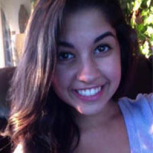 Smiling person with long dark hair in a sunlit room. This alt text was added with Al; accuracy may vary.