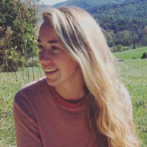 A person smiling outdoors in front of the Taj Mahal, wearing sunglasses and a striped shirt. This alt text was added with Al; accuracy may vary.