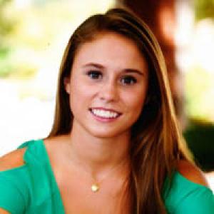 Silhouette of person with arms outstretched on a rock by the sea at sunset. This alt text was added with Al; accuracy may vary.