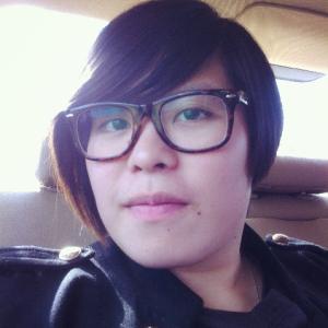 Smiling person with short hair and glasses, seated indoors. This alt text was added with Al; accuracy may vary.