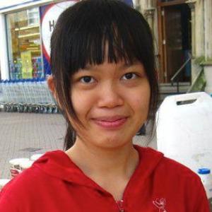 Smiling woman in a red hoodie standing outdoors. This alt text was added with Al; accuracy may vary.