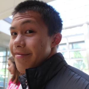 Unknown person wearing a black jacket, smiling slightly indoors. This alt text was added with Al; accuracy may vary.