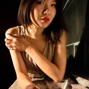 Woman smiling in a sleeveless top, standing by a window with a brick wall. This alt text was added with Al; accuracy may vary.