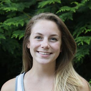 Samantha Hubbard headshot, smiling and standing in front of a tree