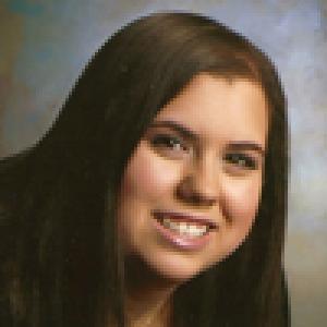 Smiling woman with long brown hair in a studio portrait. This alt text was added with Al; accuracy may vary.