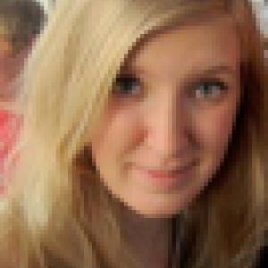 Smiling woman with long blonde hair indoors. This alt text was added with Al; accuracy may vary.