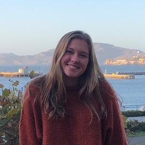 headshot of mary enright smiling in front of a waterfront background