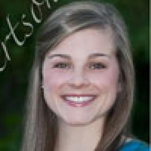 Smiling woman with brown hair against a dark background. This alt text was added with Al; accuracy may vary.