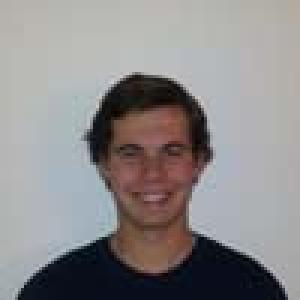 Smiling person in pink shirt against muted background. This alt text was added with Al; accuracy may vary.