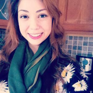 A woman smiling outdoors in an autumn forest setting. This alt text was added with Al; accuracy may vary.