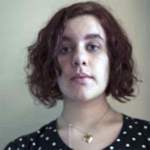 Young person with curly hair in a polka-dot shirt, wearing a heart-shaped necklace. This alt text was added with Al; accuracy may vary.