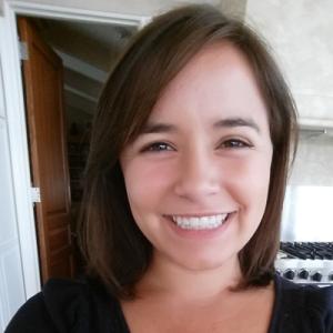 Smiling person with brown hair indoors, bright lit background. This alt text was added with Al; accuracy may vary.