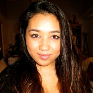 Smiling woman in pink shirt with outdoor background. This alt text was added with Al; accuracy may vary.