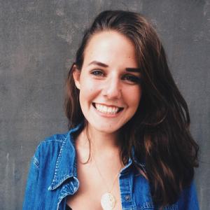 Smiling woman in a denim jacket against a gray background. This alt text was added with Al; accuracy may vary.