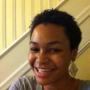 Smiling person near a staircase indoors. This alt text was added with Al; accuracy may vary.