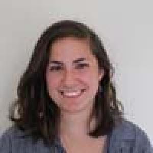 Smiling person with short hair and a striped shirt, indoors. This alt text was added with Al; accuracy may vary.