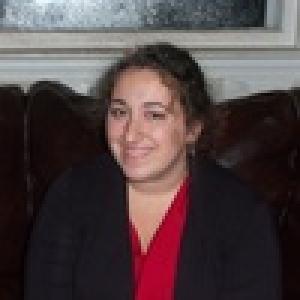 1. Person with glasses and beard wearing a light blue shirt.
2. Woman with long curly hair smiling slightly.
3. Smiling woman with long brown hair, wearing a red top.
4. Woman with shoulder-length hair, smiling, in a white shirt.
5. Woman with curly hair in a black blazer and red shirt. This alt text was added with Al; accuracy may vary.