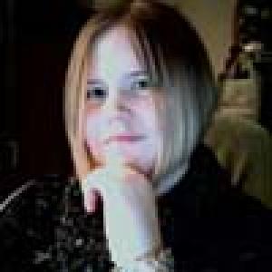 Smiling person with glasses outdoors. This alt text was added with Al; accuracy may vary.