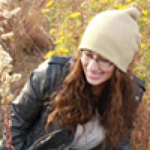 Person outdoors in autumn, wearing a beanie and leather jacket, smiling. This alt text was added with Al; accuracy may vary.