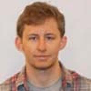 Three people, each wearing glasses or a sweater, smiling outdoors. This alt text was added with Al; accuracy may vary.