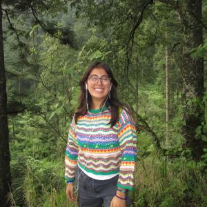 Maya standing in nature smiling at the camera