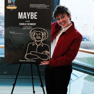 A person stands beside a film poster