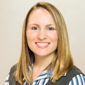Woman smiling in a grey sweater vest and striped shirt