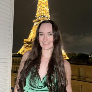 Hayley Clark smiling in front of the Eiffel Tower.