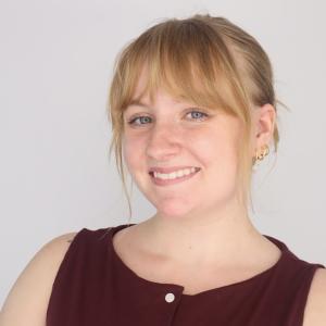 Brenley Miller smiling in front of a gray background.