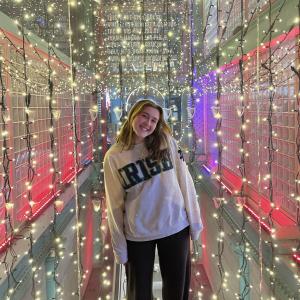 Izzy Harden standing and smiling in front of lights