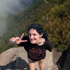 Mikayla Jensen smiling in front of a bunch of trees and a foggy sky.