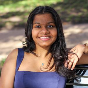 Abhigna Isukamatla smiling while sitting on a park bench.