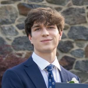 Aidan Patterson smiling in front of a stone background.